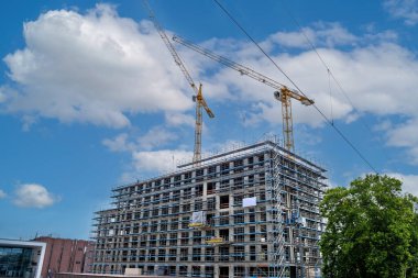 Two large construction cranes at the construction of a high-rise building in Germany.