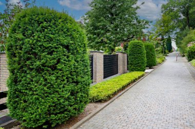 İki çit ve siyah kapılı tuğla duvar arasında tuğla yürüme.