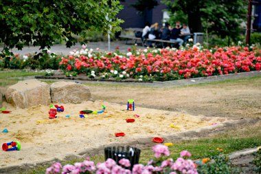 Arka planda çiçekler olan parkta çocuk oyun alanı.