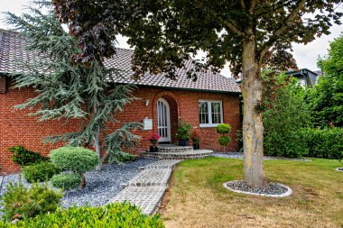 Ön bahçesinde ağaç olan tuğla ev ve Almanya 'nın ön kapısına giden yol..