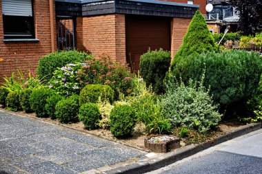 Almanya 'da bir konut tuğlası evinin yakınındaki çalıların ve taşların güzel dekoratif bir tasarımı..