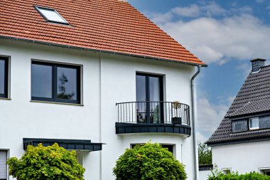 Almanya 'nın ikinci katında kırmızı çatılı ve dekoratif balkonlu beyaz bir ev..