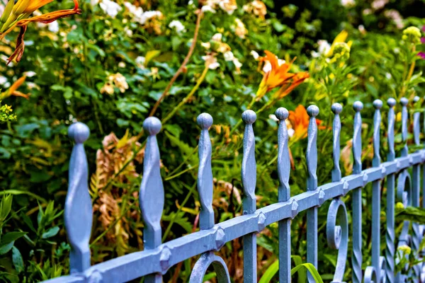 Close up of metal fence with flowers in the back ground and in the background in Germany.