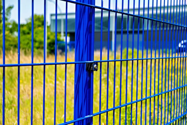 Close up of blue metal fence with building in the background in Germany.