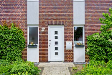 Almanya 'da özel tuğlalı bir evde pencereleri olan beyaz bir ön kapı..