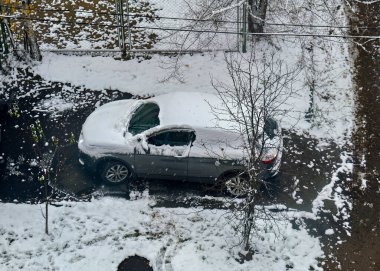 Araba çitin yakınındaki karda park halinde ve çitlerle çevrili..