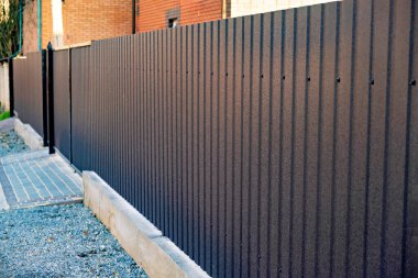 Kemerli kapı aralığı olan tuğla binanın önünde kahverengi çitler gösteriliyor..