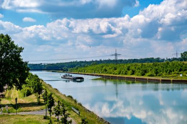 Boat is traveling down river passing under bridge in the background. clipart