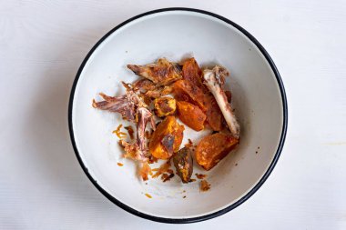 İçinde yemek artıkları olan siyah kenarlı beyaz bir kase.