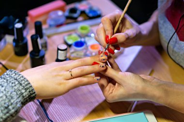 Resimde, manikür yaptıran boyalı tırnaklı bir insan görüyoruz.