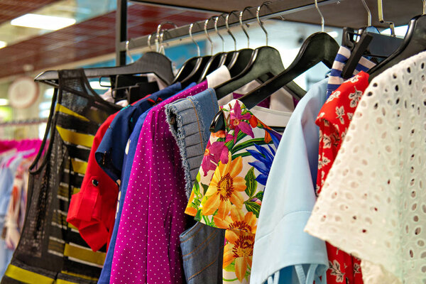 На этом изображении изображена стойка с предметами одежды, вероятно, в магазине или гардеробе