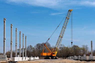 Bu görüntü merkezinde büyük sarı bir vinç olan bir inşaat alanını gösteriyor.