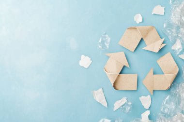 Mavi Arkaplanda Plastik Atık ile çevrili Kartondan Yapılan Çevre dostu Geri Dönüşüm Sembolü