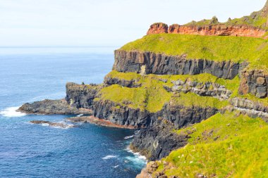 Dalgalar, Kuzey İrlanda 'nın kayalık sahillerinde, Giants Geçidi' nde, büyüleyici, altıgen kaya oluşumuna çarpıyor..