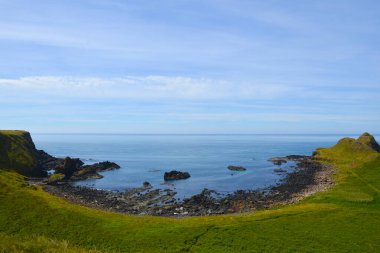 Dalgalar, Kuzey İrlanda 'nın kayalık sahillerinde, Giants Geçidi' nde, büyüleyici, altıgen kaya oluşumuna çarpıyor..