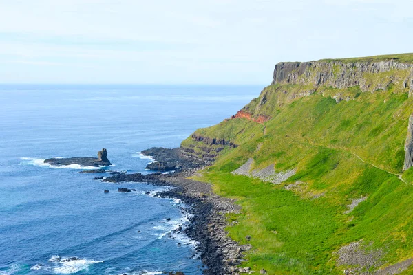Dalgalar, Kuzey İrlanda 'nın kayalık sahillerinde, Giants Geçidi' nde, büyüleyici, altıgen kaya oluşumuna çarpıyor..