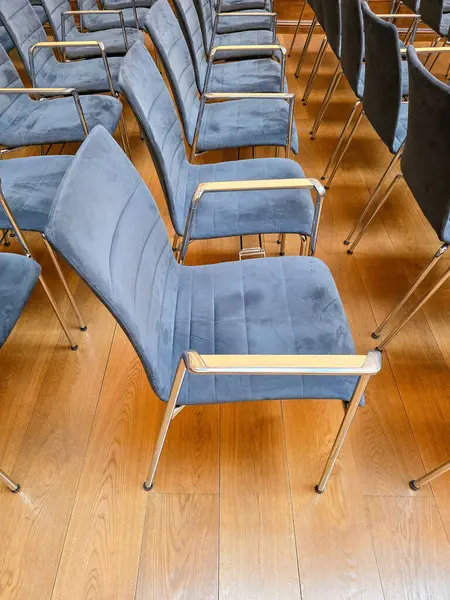 Modern bir salonda, ahşap döşemeleri olan, özdeş mavi sandalyeler, tekdüzelikte ince bir bozulma uyandırıyor.