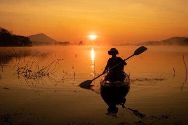 Women on kayak rows in the reservoir during the sunrise, Harirak forest park Huai Nam Man reservoir Loei Thailand 21 Jan 2023