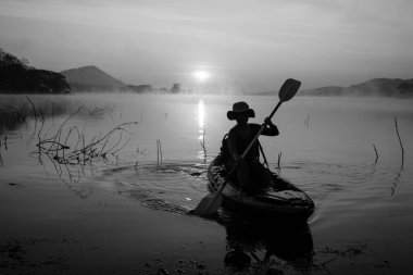 Women on kayak rows in the reservoir during the sunrise, Harirak forest park Huai Nam Man reservoir Loei Thailand 21 Jan 2023