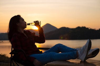 silhouette woman drinking water on the beach at dusk