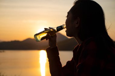 silhouette woman drinking water on the beach at dusk