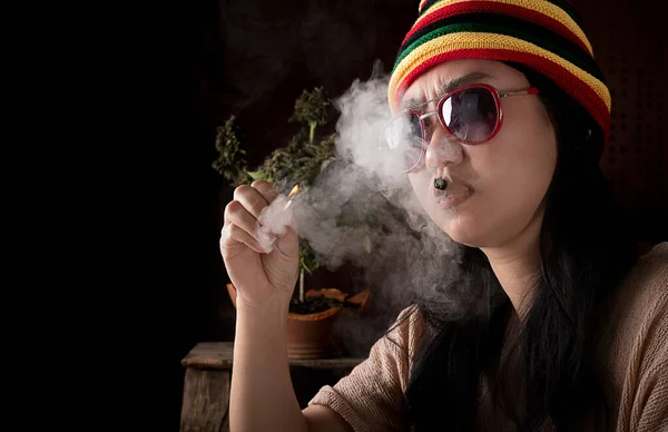 Beautiful Asia women smoking weed at cannabis tree background