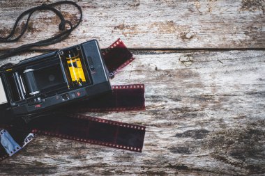 Eski bir ahşap arka planda eski bir kamera ve film kullanılmış.