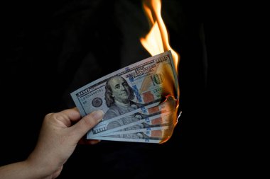 Banknot tutan bir el yanıyor, nakit para iş ödemesini ve finansal başarıyı simgeliyor
