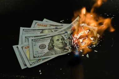 Yığın banknot, iş ödemelerini ve mali başarıyı simgeleyen siyah bir arkaplanda yanıyor