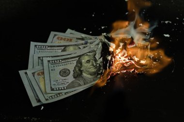Yığın banknot, iş ödemelerini ve mali başarıyı simgeleyen siyah bir arkaplanda yanıyor