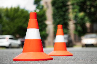 Parlak kırmızı turuncu trafik konileri şehirdeki bir asfaltta sıra sıra bekliyor. Düşük açı. Kapat. 