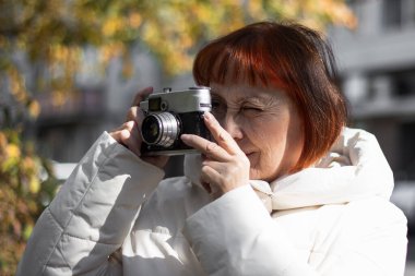 Dinlenme, rahatlama, yaşam tarzı konsepti. Beyaz kadın retro kamerayla fotoğraf çekiyor. Sonbahar mevsimi 