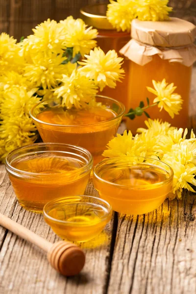高齢者の木製の背景に瓶やプレートで蜂蜜 異なるサイズのプレート内の蜂蜜の組成物は 黄色の花を散布します オーガニック ハニー 健康食品 蜂蜜と花の静物画 — ストック写真