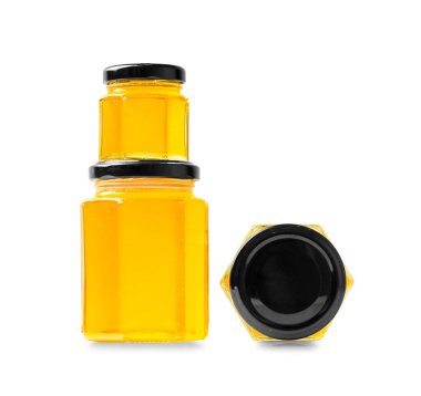 Creative composition of glass jars in the form of honeycombs different size with honey closed with black lids on a white background close-up. Glass jars with organic honey in different positions on isolation.