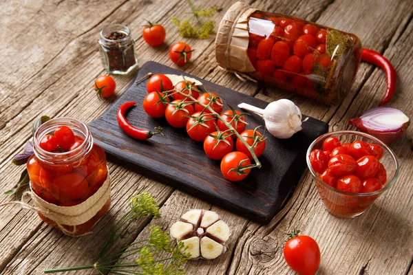 Canned tomatoes in closed jars with spices on a wooden background. Harvesting tomatoes for the winter. Canning tomatoes with garlic, pepper, dill and basil.