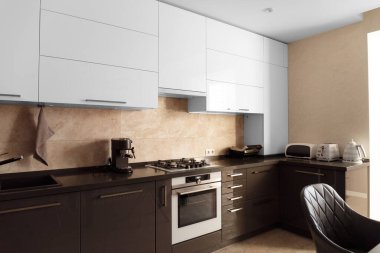Modern kitchen in the apartment. Kitchen space design. Gray kitchen interior with white cabinets. Coffee maker, toaster, electric kettle, electric grill and built-in oven in the interior of the kitchen.