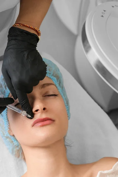 Facial treatments. The concept of maintaining health, youth and beauty. Modern cosmetology, beautician tools, gloved hands. beauty techniques. beauty injections. Lip augmentation with fillers.