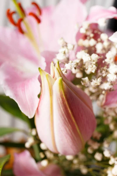 Çiçek açan zambakların arka planına yakın pembe bir zambak tomurcuğu. Güzel bir buket çiçek makro pozu