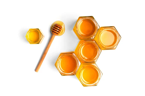 在开放的罐子里 蜂蜜以蜂窝和白色背景顶部的木制围裙的形式创造性地组合在一起 有机蜜蜂产品的概念 被隔离的蜂蜜 — 图库照片