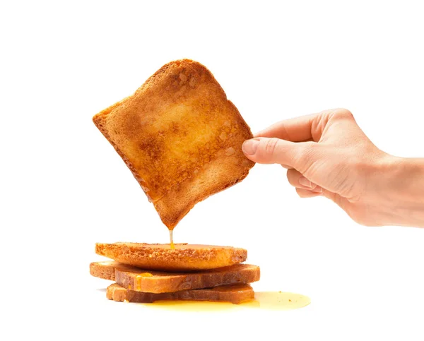 白い背景のクローズアップに蜂蜜と手に1つのトーストでトーストしたパンのスライスを食欲をそそる 蜂蜜は白いトーストしたパンのスライスに注ぐ — ストック写真
