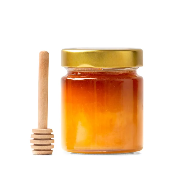 玻璃瓶中的有机蜂蜜和白色底座上的木制搅拌器 蜂蜜棒和新鲜蜂蜜在封闭的罐子中隔离特写 健康产品 — 图库照片