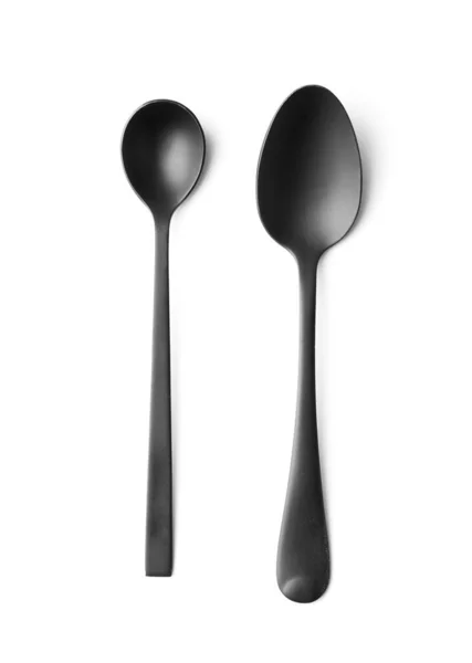 Black matte metal spoons on a white background top view, black cutlery on white insulation.
