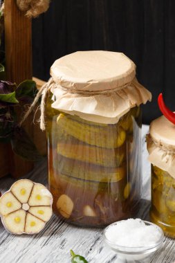 Kavanozda salatalık turşusu, kırmızı biber, fesleğen, ahşap arka planda sarımsak. Salatalık turşusu..
