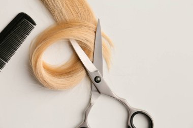 Scissors and piece of blond hair. Professional barber hair cutting shears on background. Hairdresser salon equipment concept, premium hairdressing set. Accessories for haircut with copy space