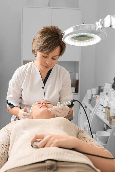 Rejuvenating facial therapy treatment at spa salon clinic. Young beautiful woman getting lifting anti-aging, face massage and skincare by electroporation facial therapy aesthetic cosmetology.