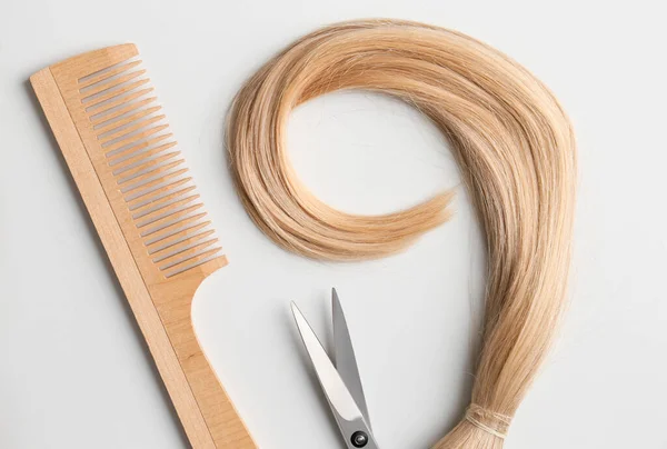 Flat lay composition with light blond hair, comb, scissors and space for text on background. Hairdresser service
