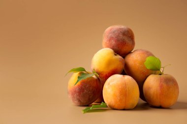 A pile of fresh peaches on a brown background. A handful of raw peaches on a brown background. Useful dietary product.