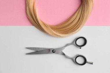 Scissors and piece of blond hair. Professional barber hair cutting shears on background. Hairdresser salon equipment concept, premium hairdressing set. Accessories for haircut with copy space