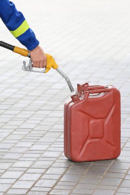 A man fills jerry cans at a gas station. A man fills gasoline in a canister at a gas station. Pouring gasoline into a canister. Collecting funds to buy fuel.