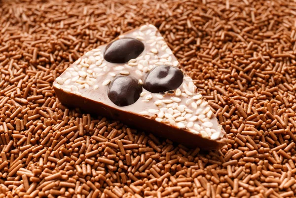 Chocolate background. A piece of chocolate pizza with nuts lies in a chocolate crumb close-up. The concept of confectionery.